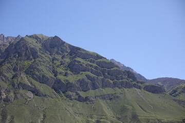 Caucasian mountains in sunny weather, green dense forests on the mountains and snowy peaks of the old high mountains of Georgia