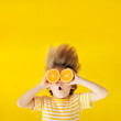 © Sunny studio - Surprized child holding slices of orange fruit like sunglasses
