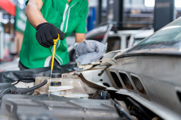 Wall Mural - Auto mechanic checking the engine oil. For customers who use car for repair services, the mechanic will work in the garage.