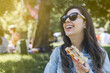 young latina woman smiles and eats a waffle at an outdoor summer concert or music festival