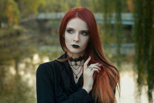 Beautiful Fashionable Young Girl Witch Model Stands Outdoors In The Forest In Autumn By The River, Pale, Vampire, Goth