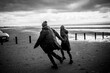 © Caia Image - Couple holding hands running on winter beach