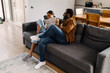 © Drobot Dean - Black girl making fun with her father while sitting on sofa
