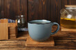 Mug of hot drink and stylish cup coaster on wooden table