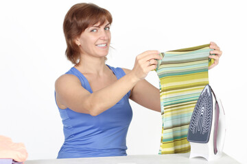 Wall Mural - Young smiling woman is ironing a shirt with a shirt iron on white background.