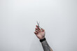 © alones - Creative male hand with a tattoo holding scissors against a white background. Barber shop and haircuts, concept