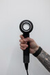 © alones - Male hand holds a modern hair dryer against a white background. Professional Barber