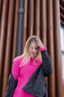 Fashion happy young woman with pink sweater and jacket walks on the street. Happiness emotions
