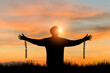 © Tarokmew - Silhouette of freedom young man standing alone with beautiful sky at sunset open both arms with chains on his arms. He felt free from the shackles tied to his arms.