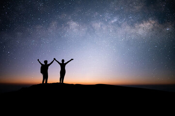 Wall Mural - Silhouette young couple traveler and backpacker watched the star and milky way on top of the mountain. They enjoyed traveling and was successful when he reached the summit.