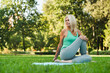 Mature fit woman stretching her body on fitness mat, doing workout in park, practicing breathing exercises. Active healthy lifestyle.