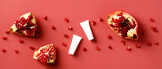 Wall Mural - natural pomegranate cosmetics on red background. white cosmetic tubes with slices of pomegranate and