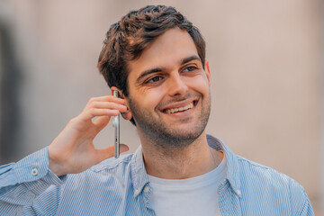 Wall Mural - portrait of young man talking on mobile or cell phone in the street