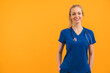 © PoppyPix - attractive blonde Caucasian nurse smiling on orange background copy space studio shot medium shot medical concept. High quality photo