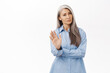 No thank you. Asian senior woman with grey hair, showing stop, rejectiong gesture, wave hand to refuse smth, standing over white background