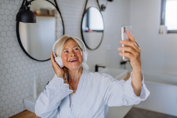 Poster - Beautiful senior woman in bathrobe listening to music in bathroom, relax and wellness concept.