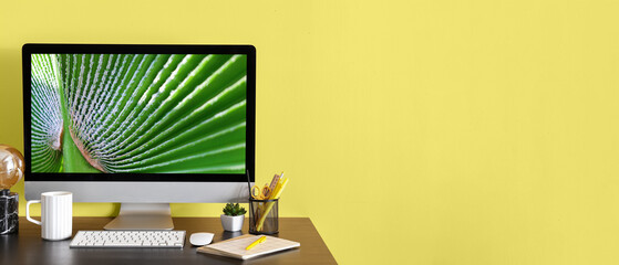 Comfortable workplace with modern computer on yellow background with space for text