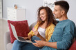 © Pixel-Shot - Young couple ordering something online on sofa at home