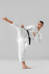 Wall Mural - Man practicing karate on light background