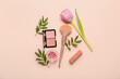 Decorative cosmetics with brush, tulip and plant branches on pink background. Mother's Day celebration