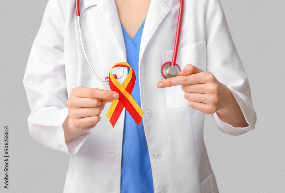Female doctor pointing at awareness ribbon on grey background. Hepatitis concept