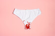 White women's panties with red flower sequins on a pastel pink background.