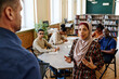 © pressmaster - Muslim woman wearing hijab standing in front of English language teacher retelling story during lesson for immigrants