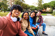 © Daniel - Group of multiracial college student friends taking selfie with phone outside. Students laughing and having fun in park.