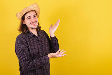 Man wearing typical clothes for party Junina. presenting with hands, space for advertising and text.