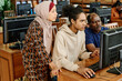 © pressmaster - Group of three immigrant students spending in modern library searching something together in internet on computer