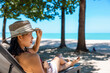 © TripleP Studio - Model Asian woman wearing red swimsuit and straw hat sits in sun by the sea. Beautiful girl relaxing at infinity luxury resort. Spa, wellness