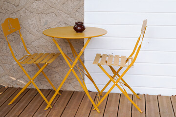 metal colorful yellow chair seat table in summer in street front bar wooden wall