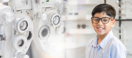 Wall Mural - Banner style, Smiling Indian-thai boy choosing glasses in optics store, Portrait of Mixed race ethnicity kid wearing glasses at optical store