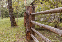 Large Wooden Fence Posts That Enclose An Old Wooden House In The Forest. How People Built Houses And Fences In The Past. Ecological Construction And Materials.