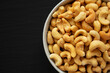 Homemade Roasted and Salted Cashews in a Bowl on a black background, top view. Flat lay, overhead, from above.