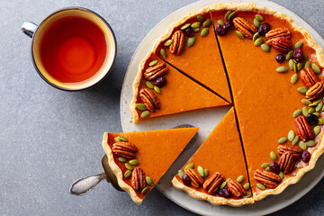 Wall Mural - Pumpkin pie, tart made for Thanksgiving day with cup of tea. Grey stone background. Close up. Top view.
