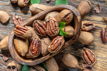 Wall Mural - Shelled and cracked pecan nuts in the wooden bowl on wooden table. Top view.