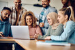 © Drazen - Group of happy students and their teacher using laptop during class at university.
