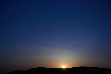 Wall Mural - sunset above mountain and blue dark night sky with stars