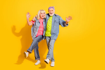 Photo of funky cute husband wife wear jeans shirts dancing walking empty space isolated yellow color background