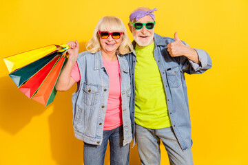 Poster - Photo of excited confident husband wife wear jeans shirts having shopping thumb up isolated yellow color background