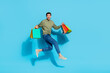 Full size photo of crazy handsome guy hurry rush hold packages jump isolated on blue color background