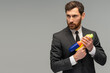 Portrait of a serious businessman standing with water gun against grey background and looking away with calm face