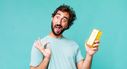 Wall Mural - young adult hispanic crazy man holding a gold ingot