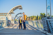 Dad And Son Tourists On The Background Of The Moscow Footbridge In Podgorica. The Metal Construction Of This Pedestrian Bridge Was A Gift By The City Of Moscow To The People Of Montenegro. Built In
