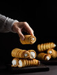 © nndanko - A woman's hand holds a baked tube with whipped protein cream, black background