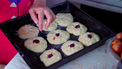 Wall Mural - Cooking sweet pastries with cherries. Baking dough on a baking sheet