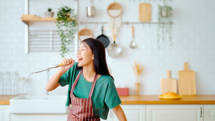 Asian young woman dancing in kitchen room. Female happy and relaxing at free time on weekend