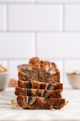 Wall Mural - Slices of Chocolate banana bread with walnuts on a marble board and ingredients on a grey neutral background