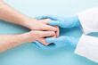 Doctor's hands in medical gloves holding man's hands.